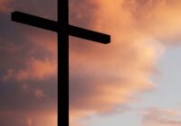 silhouette of large cross under orange sky