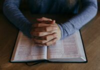 man holding his hands on open book
