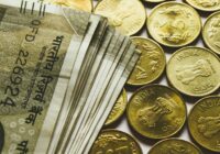 round gold-colored rupee coins and banknotes