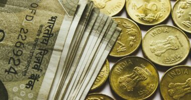 round gold-colored rupee coins and banknotes