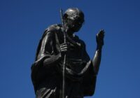 Statue of mahatma gandhi against a clear blue sky.