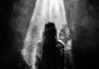 photograph of person facing opposite in smoky spotlight