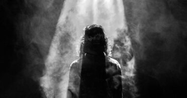 photograph of person facing opposite in smoky spotlight